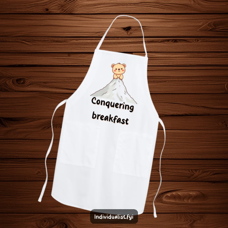 Funny bear cub apron showing a happy cub scaling a miniature mountain, perfect for adding humor to cooking and baking.