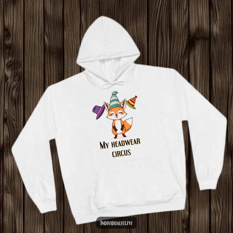 Funny hoodie featuring a spirited fox juggling three different colored, eccentric hats, perfect for cozy and playful relaxation.